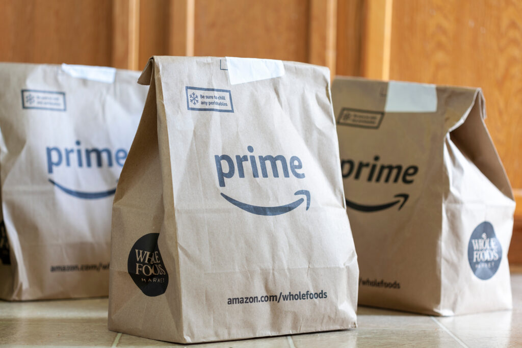 Clarksburg, MD, USA 05-12-2021: Three recycled paper grocery bags with Amazon Prime and Whole Foods supermarket logos. Amazon offers free same day delivery of all grocery items for its prime members.