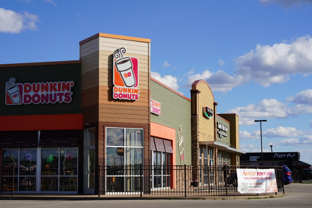 Dunkin Donuts brand sign on store building.
By Aaron