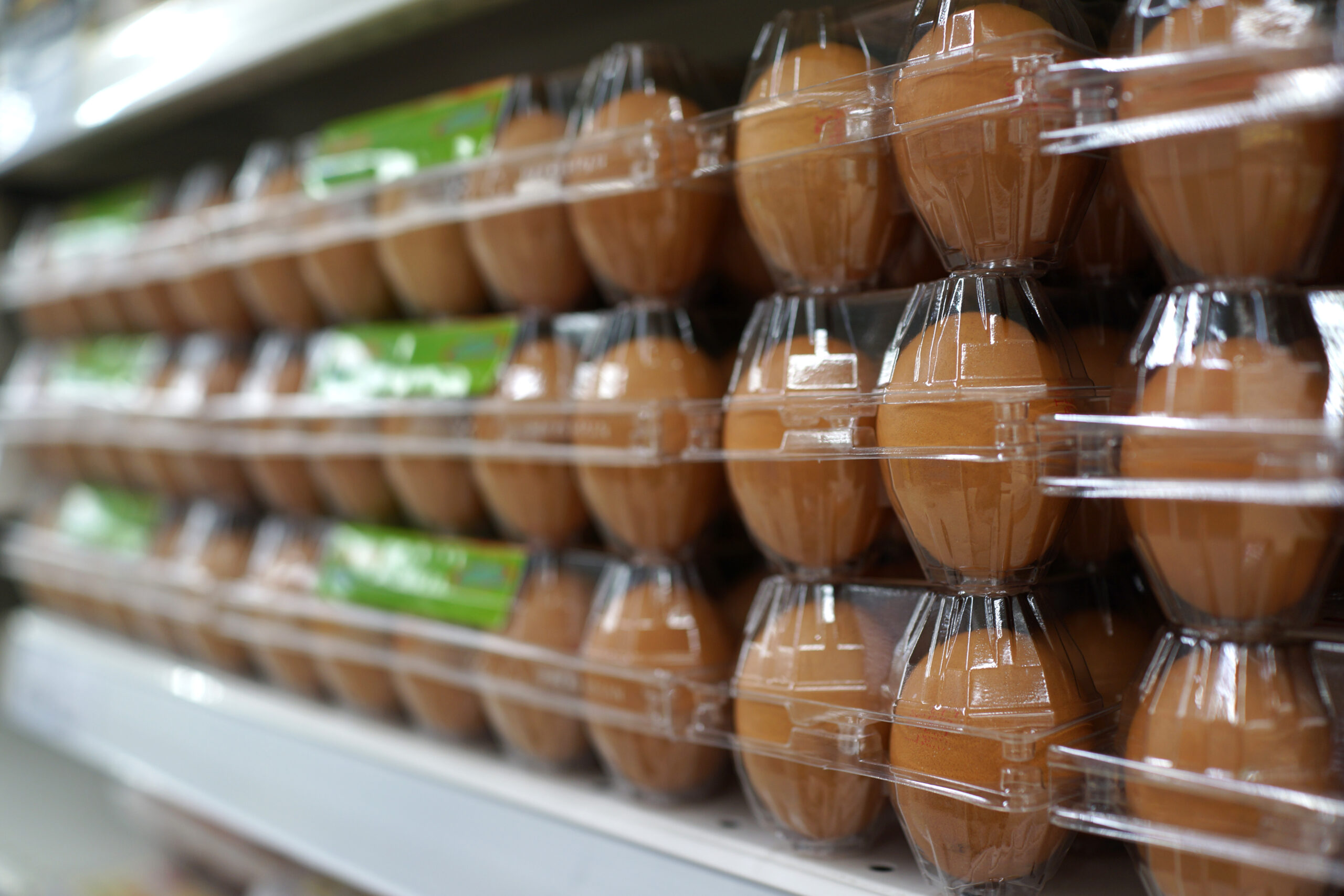 Stacks of brown eggs in a transparent plastic case display on the shelf in a grocery store.
By ltyuan